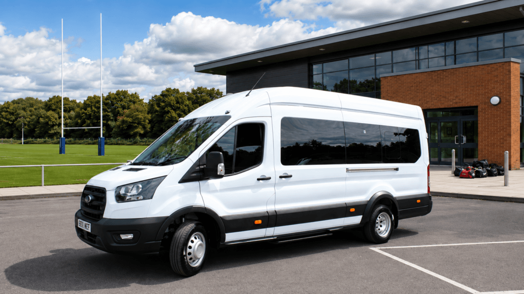 White Ford transit 17 seat minibus in front of school playing field